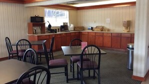 A dining area with a long counter, several chairs, and a television. - Stratford House Inn and Suites (Temple)