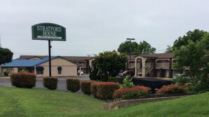 A motel named Stratford House with a sign, a parking lot, and a building with a blue roof. - Stratford House Inn and Suites (Temple)