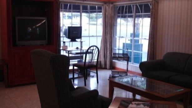 A living room with a television, a sofa, a chair, and a coffee table. - Stratford House Inn and Suites (Temple)