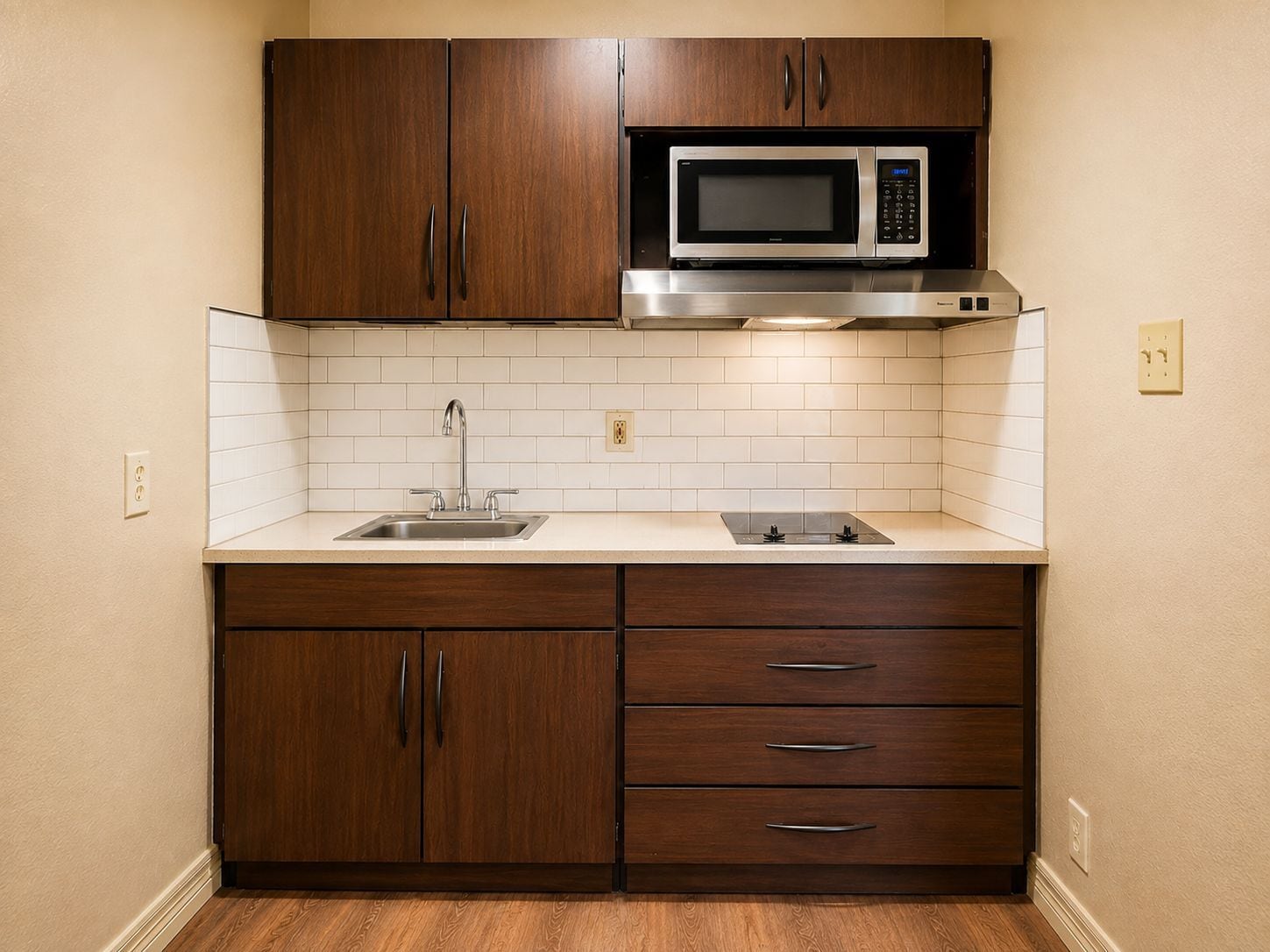 A kitchen with wooden cabinets, a stainless steel sink, a microwave, and a gas stove.