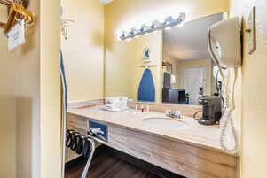 Un baño de hotel con lavamanos de mármol, un espejo con iluminación, un secador de pelo y un teléfono.