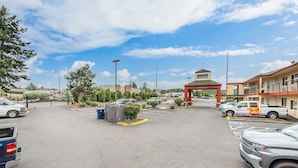 Un parking avec une entrée menant à un bâtiment, un espace d’attente abrité et une enseigne bien visible indiquant un hôtel ou un motel.