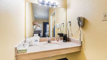 A bathroom with a sink, mirror, and hairdryer on the wall.