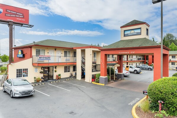 A Days Inn with a clear entrance, a parking lot, and a sign indicating a clearance of 13'6". - Days Inn by Wyndham Federal Way (Federal Way)
