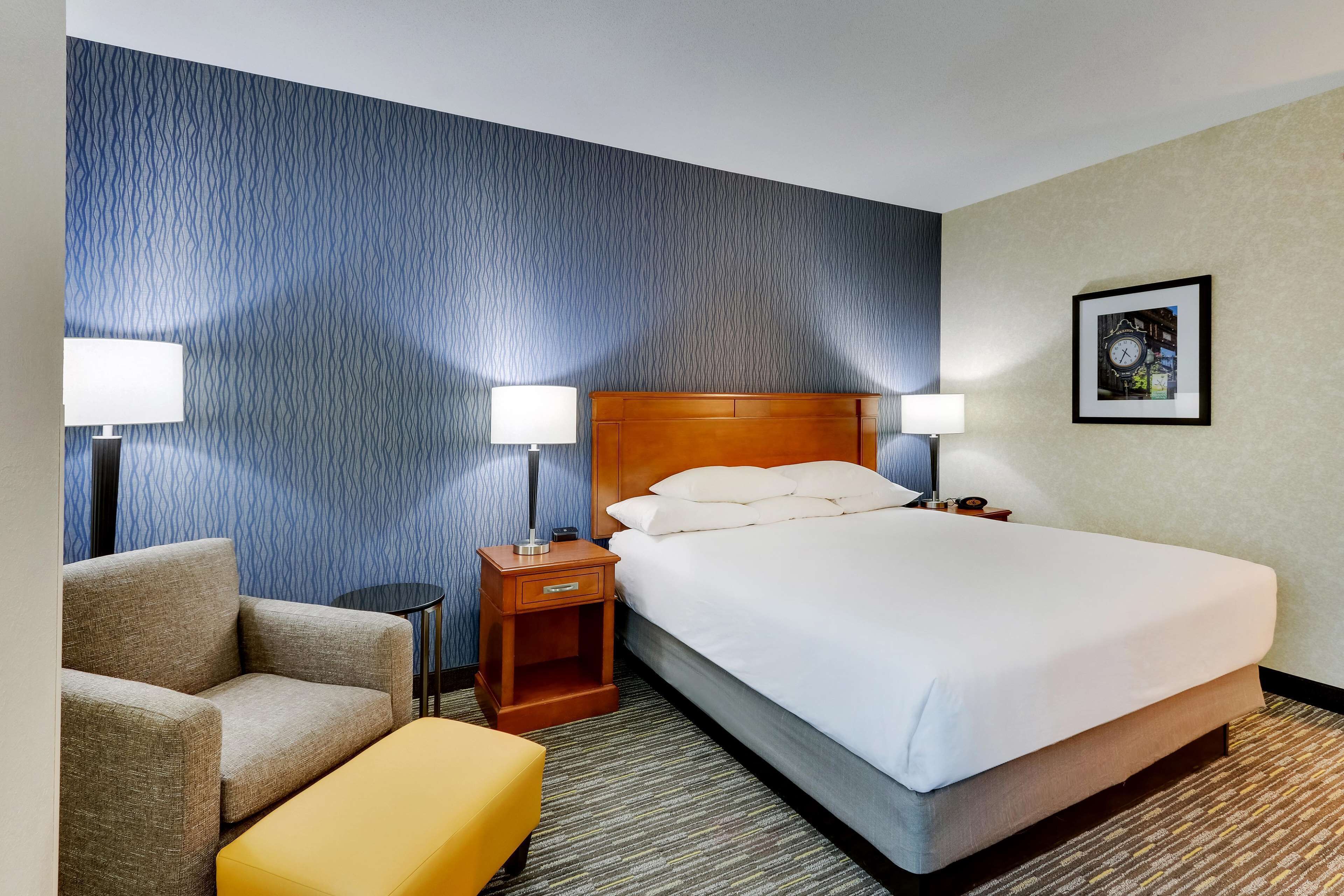 A hotel room with a large bed, two bedside tables with lamps, a sofa, and a small table.