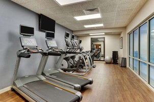 Un gimnasio con cintas de correr, elípticas y un espejo grande.