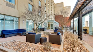 An outdoor seating area with sofas and planters, surrounded by a building with large windows and a brick wall. - Drury Inn & Suites Sikeston, MO (Sikeston)
