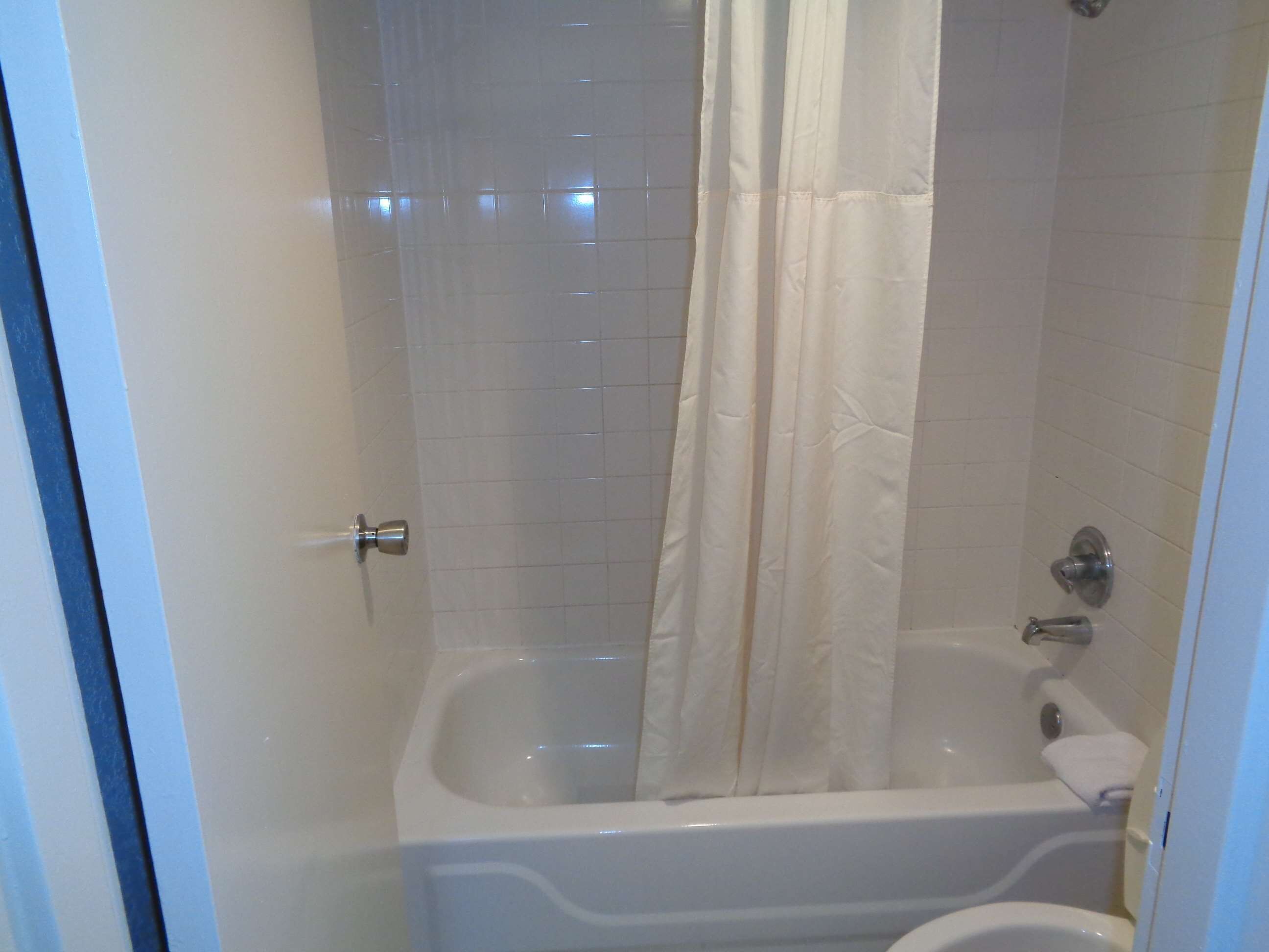 A bathroom with a bathtub, a shower curtain, and a toilet.