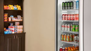 A refrigerator stocked with various beverages and snacks, including sodas, energy drinks, and packaged foods. - Super 8 by Wyndham Gulfport Airport NW/Near Biloxi (Gulfport)