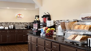 A breakfast buffet area with a coffee station, fruit bowl, and bread display. - Super 8 by Wyndham Gulfport Airport NW/Near Biloxi (Gulfport)
