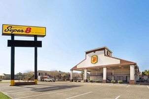 A Super 8 hotel with a large sign, a covered parking area, and a building with a balcony.