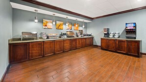 A hotel kitchen with a long counter, various food display cases, and a coffee machine.