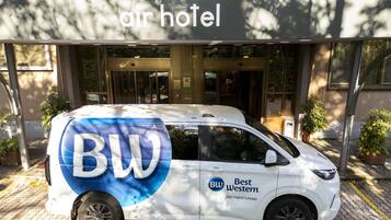 Uma carrinha branca estacionada em frente a um hotel com um letreiro em cima.