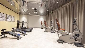 Une salle de sport équipée de tapis de course, de vélos d’appartement et d’appareils elliptiques.