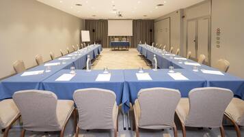 A conference room with a long table, chairs, a projector screen, and a whiteboard.