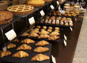 Une vitrine de boulangerie présentant diverses pâtisseries, comme des tartes, des croissants et des muffins.