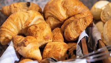 Ein Korb mit verschiedenen Brotsorten, darunter Croissants und Baguettes.