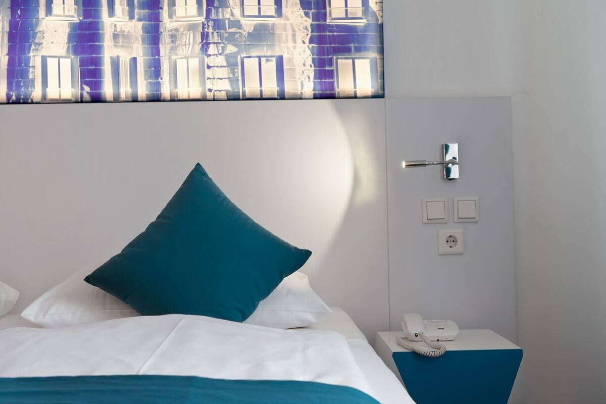 Une chambre d’hôtel avec un lit, une table de chevet avec un téléphone et un interrupteur fixé au mur.