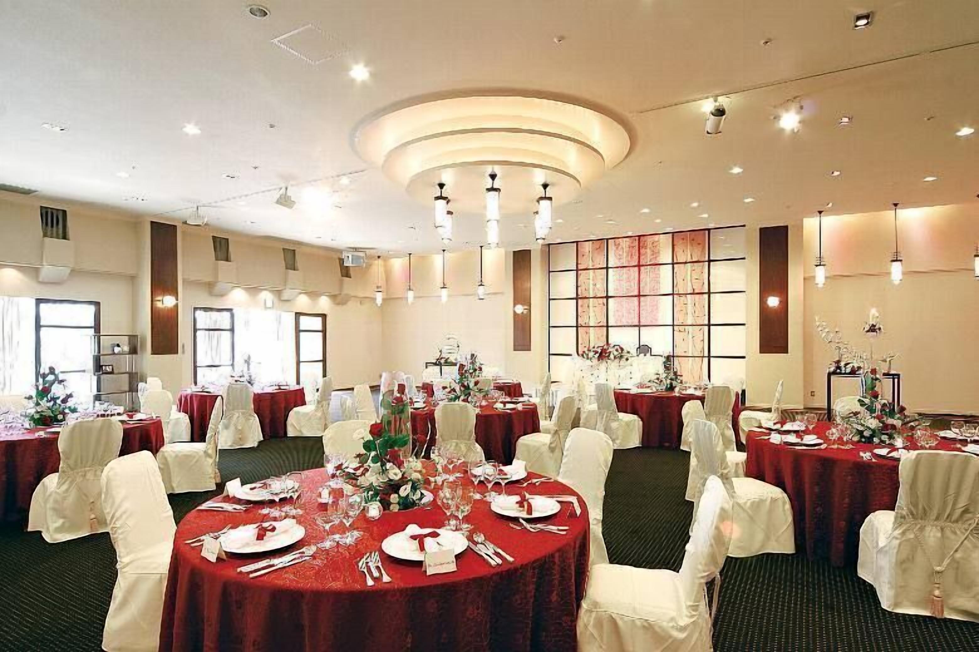 A banquet hall with round tables set for dining, white chairs, and a central decorative wall.