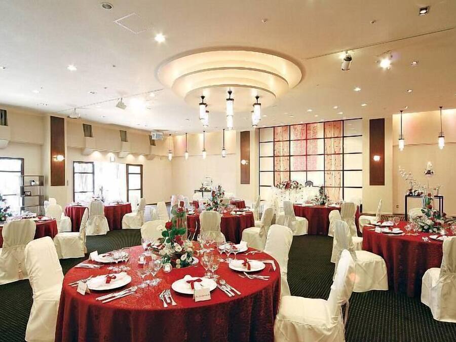 A banquet hall with round tables set for dining, white chairs, and a central decorative wall.