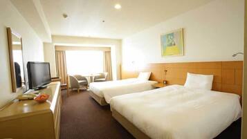 A hotel room with two beds, a desk with a television, a chair, and a painting on the wall.
