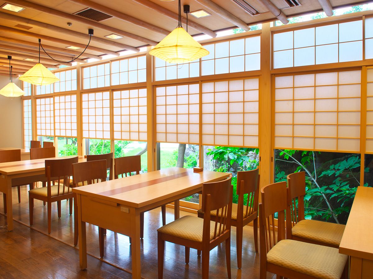 A traditional Japanese-style dining area with wooden tables and chairs, large windows with shoji screens, and hanging paper lanterns.