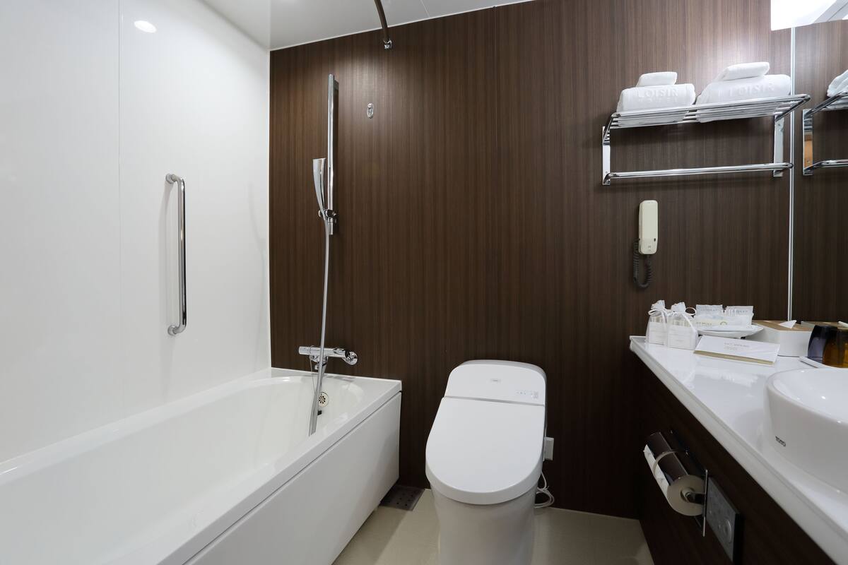 Un baño moderno con bañera, inodoro y tocador con estantes.