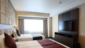 Een hotelkamer met twee bedden, een televisie en een groot raam met gordijnen.