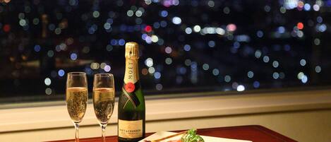 A table with two glasses of champagne, a bottle of Moet & Chandon champagne, and a plate of food.
