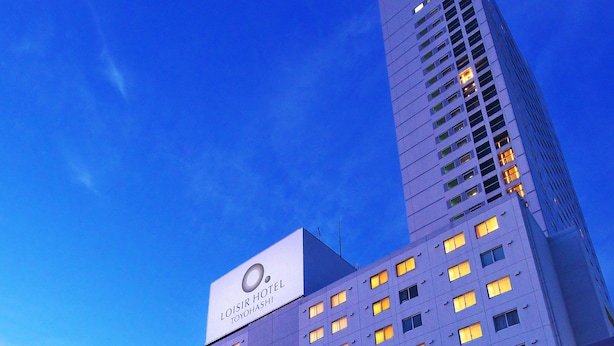 Een hotel met een moderne gevel, grote ramen en een opvallende entree met een overdekt gedeelte.