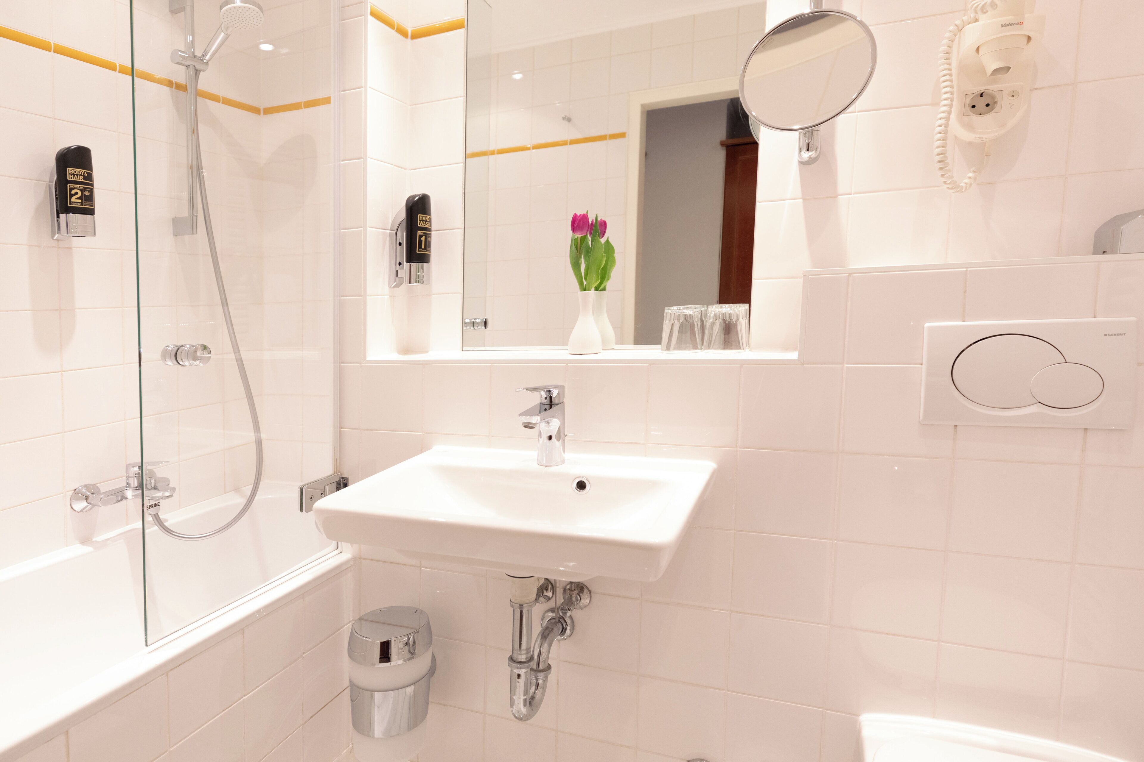 A modern bathroom with a glass-enclosed shower, a white sink, and a mirror above it.