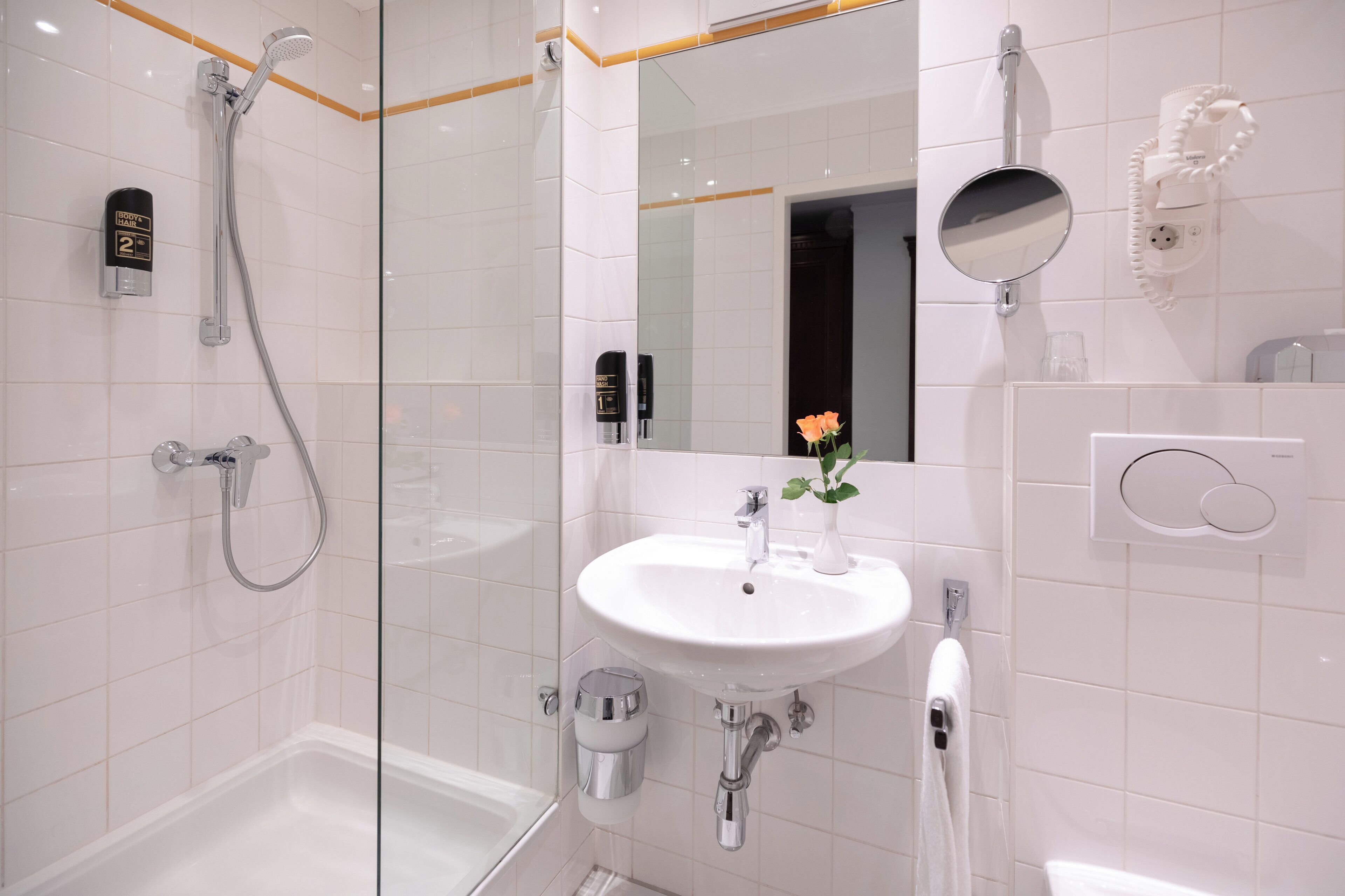 A modern bathroom with a glass-enclosed shower, a white sink, and a mirror.