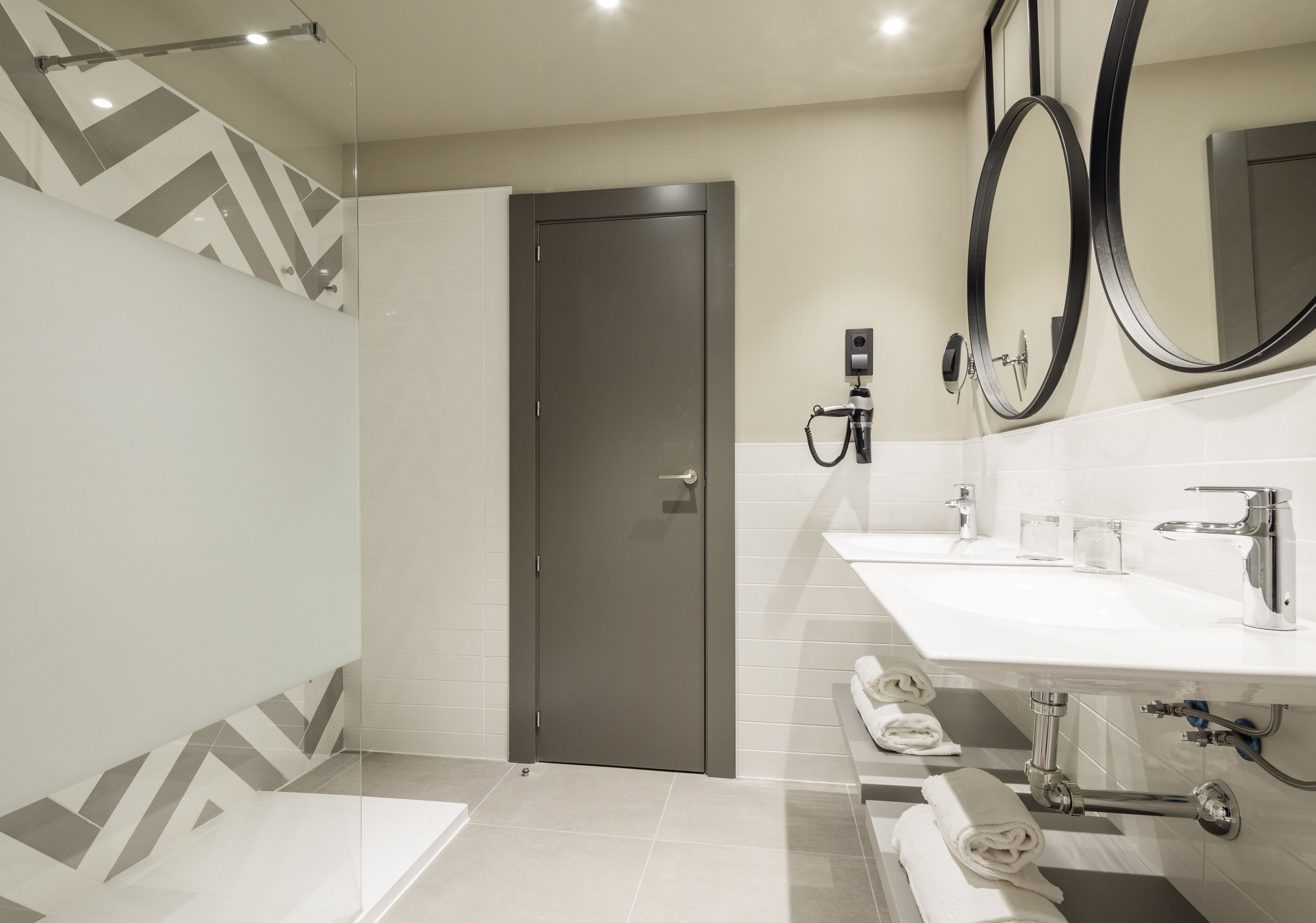 A modern bathroom with a shower, a toilet, a sink with a mirror, and a towel rack.