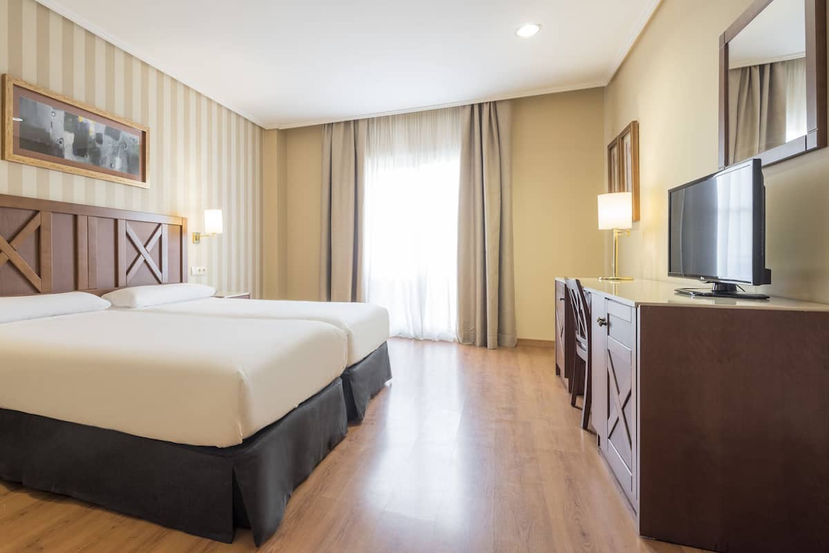 Een hotelkamer met een groot bed, een televisie, een bureau en een dressoir.