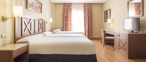 A hotel room with two beds, a desk, a chair, a television, and a large window with curtains.