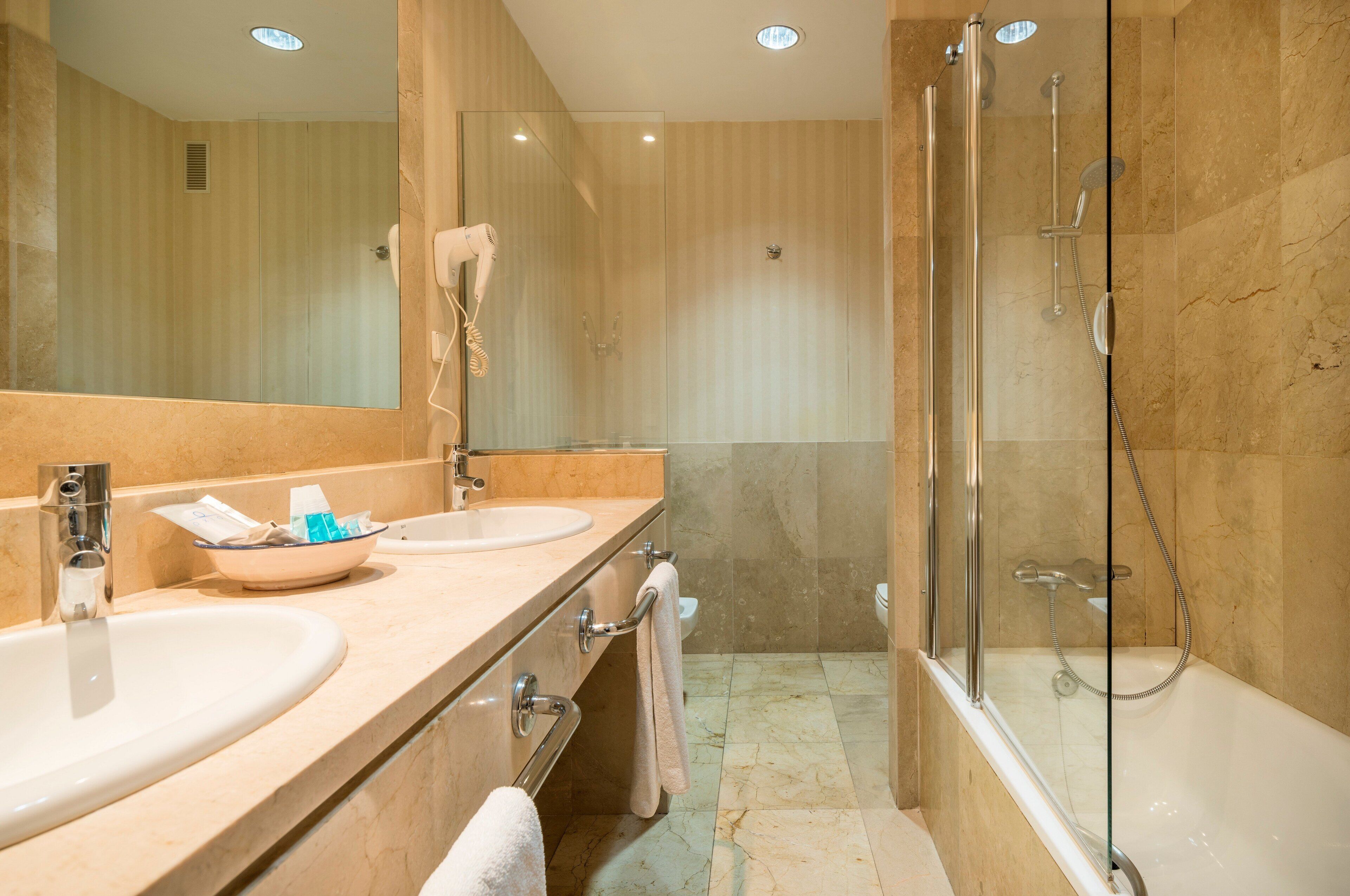 Un baño moderno con dos lavabos, cabina de ducha de cristal y un espejo grande.
