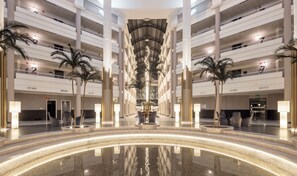 Un atrium à plusieurs niveaux, doté d’un bassin central aux reflets changeants, de palmiers et d’un design moderne.