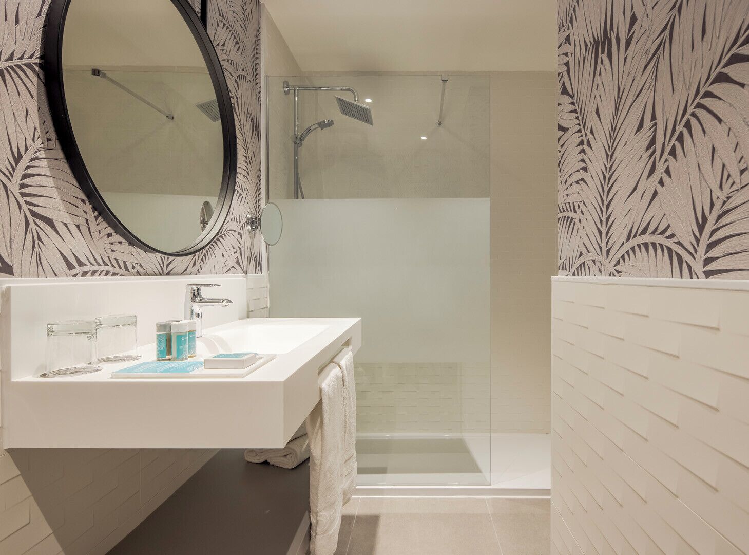 A modern bathroom with a white vanity, a large mirror, and a glass-enclosed shower.