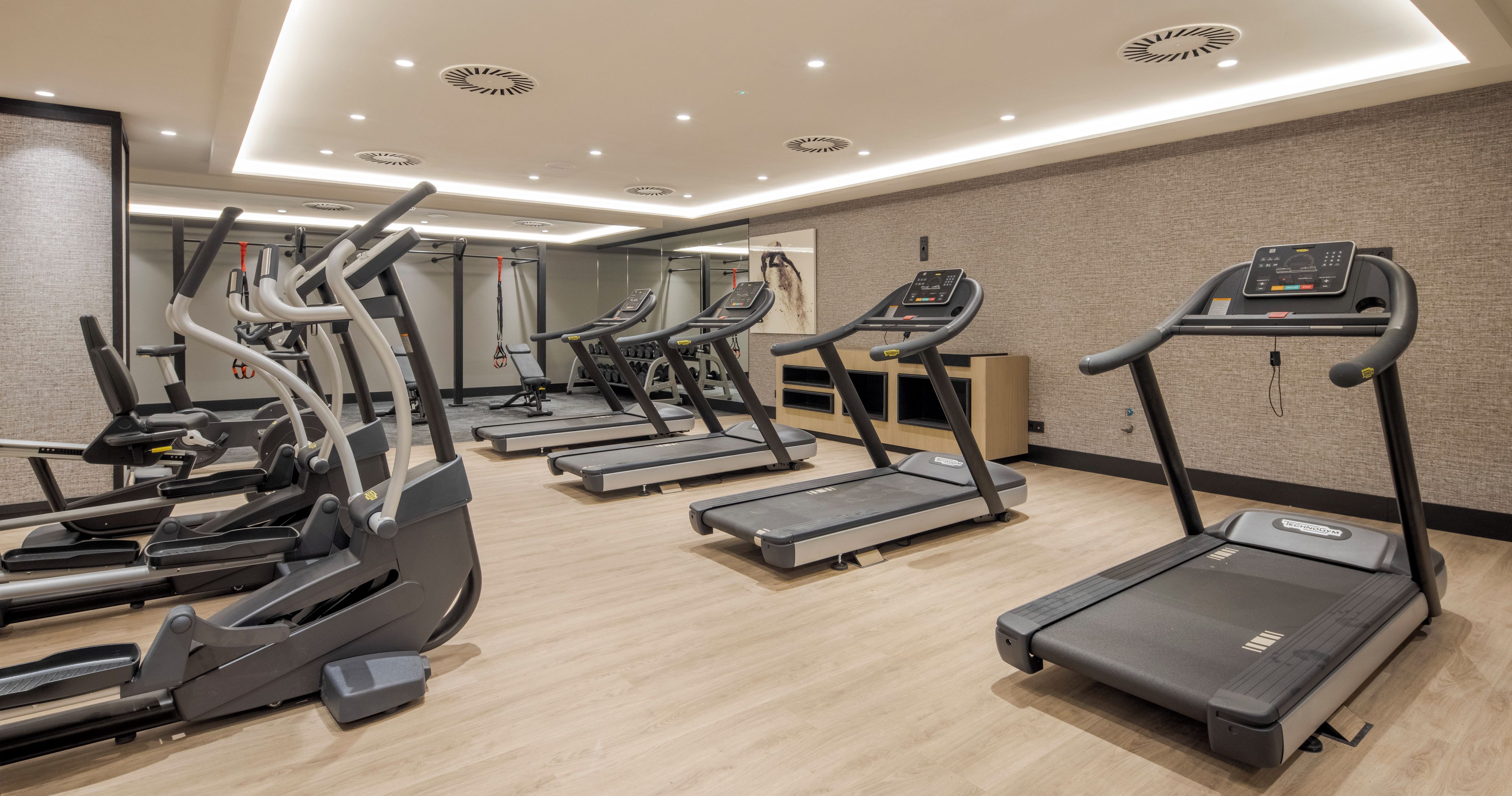 A gym with multiple treadmills, elliptical machines, and weight equipment.