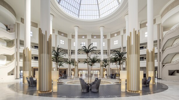 A spacious lobby with a central seating area, multiple floors, and a large skylight. - Hotel ILUNION Alcora Sevilla (San Juan de Aznalfarache)
