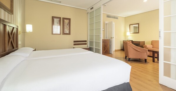 Habitación de hotel con una cama grande, un escritorio con silla, un armario y un espejo en la pared.