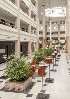 Un hall d’entrée spacieux, avec de nombreux étages, de grandes colonnes et des plantes en pot.