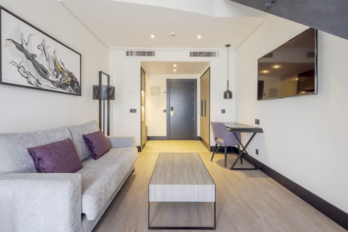Een moderne woonkamer met een bank, salontafel en een eethoek met een stoel en tafel.