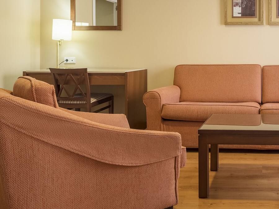 A living room with a sofa, a chair, a coffee table, a desk, and a lamp.
