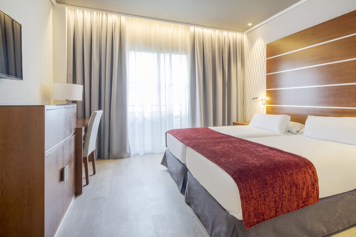 Een hotelkamer met een groot bed, een houten hoofdbord, een bureau en een stoel.