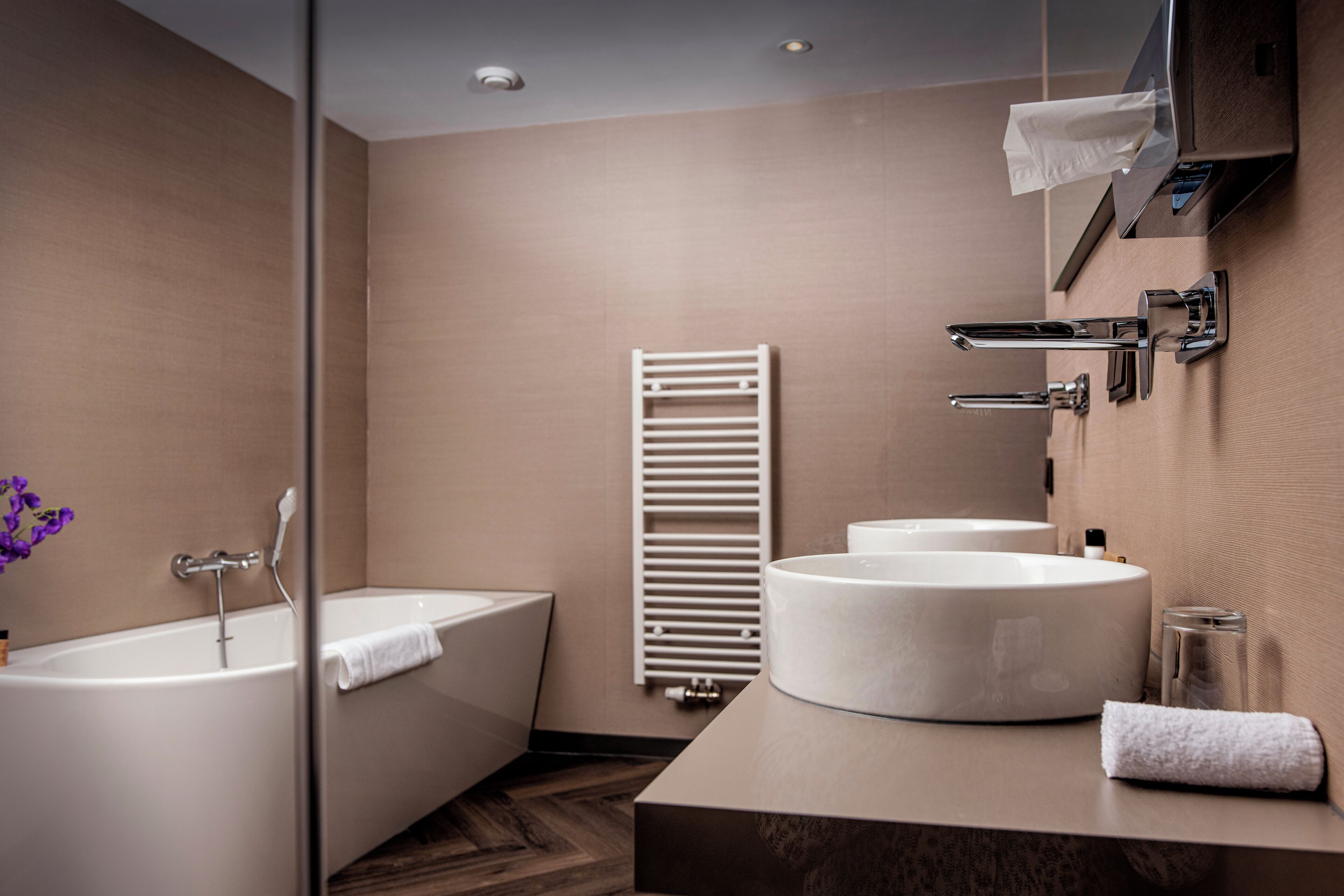 Ein modernes Badezimmer mit einer Badewanne, zwei Waschbecken und einem Handtuchhalter.