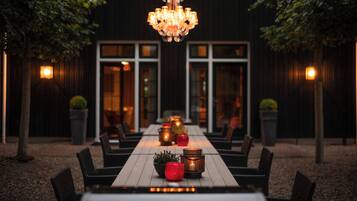 An outdoor dining area with a long table, chairs, and a chandelier.