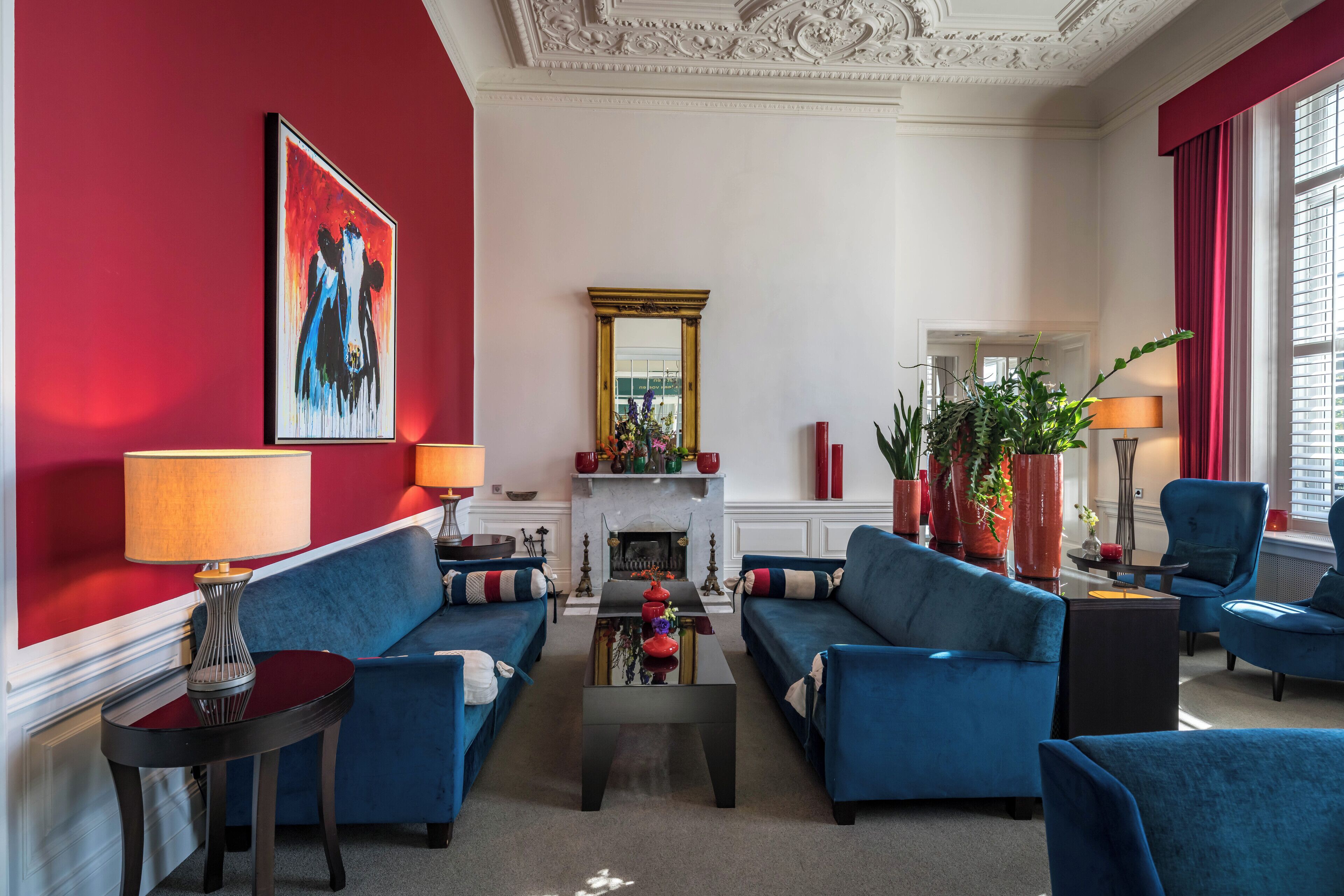 A modern living room with blue sofas, a fireplace, and red walls.