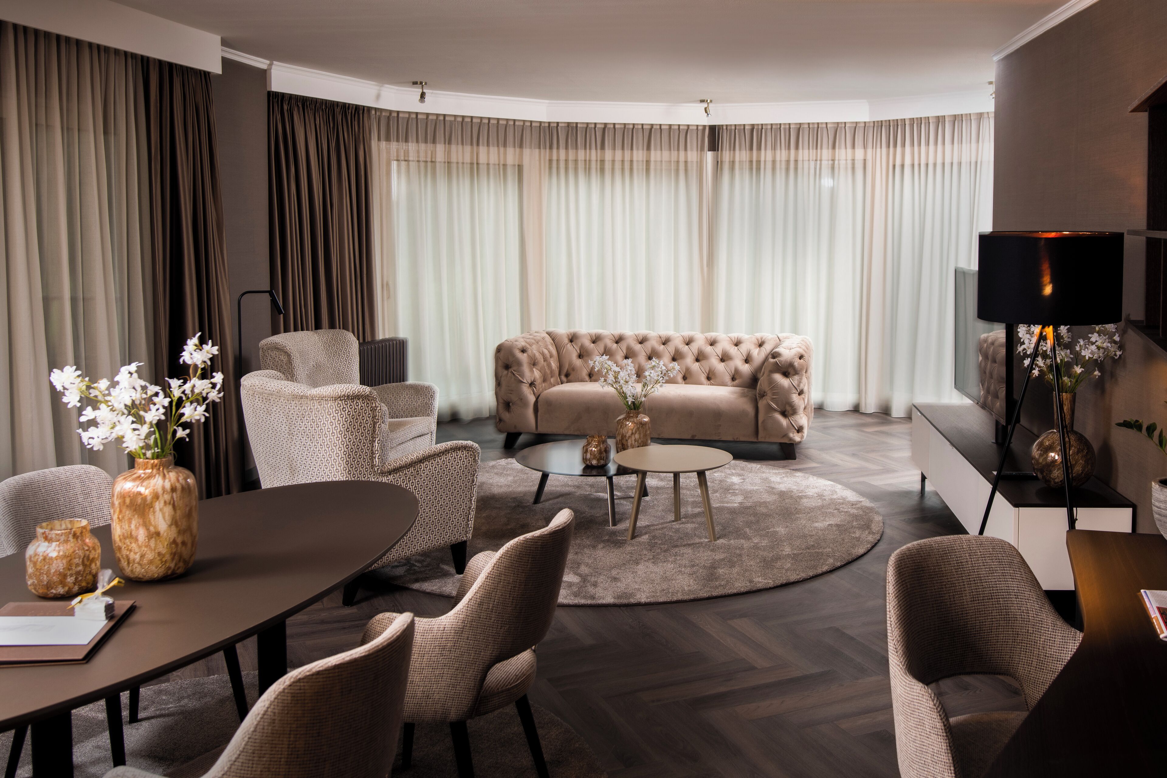 Un salon moderne avec un canapé capitonné, une table basse ronde et un coin repas comprenant une table et des chaises.