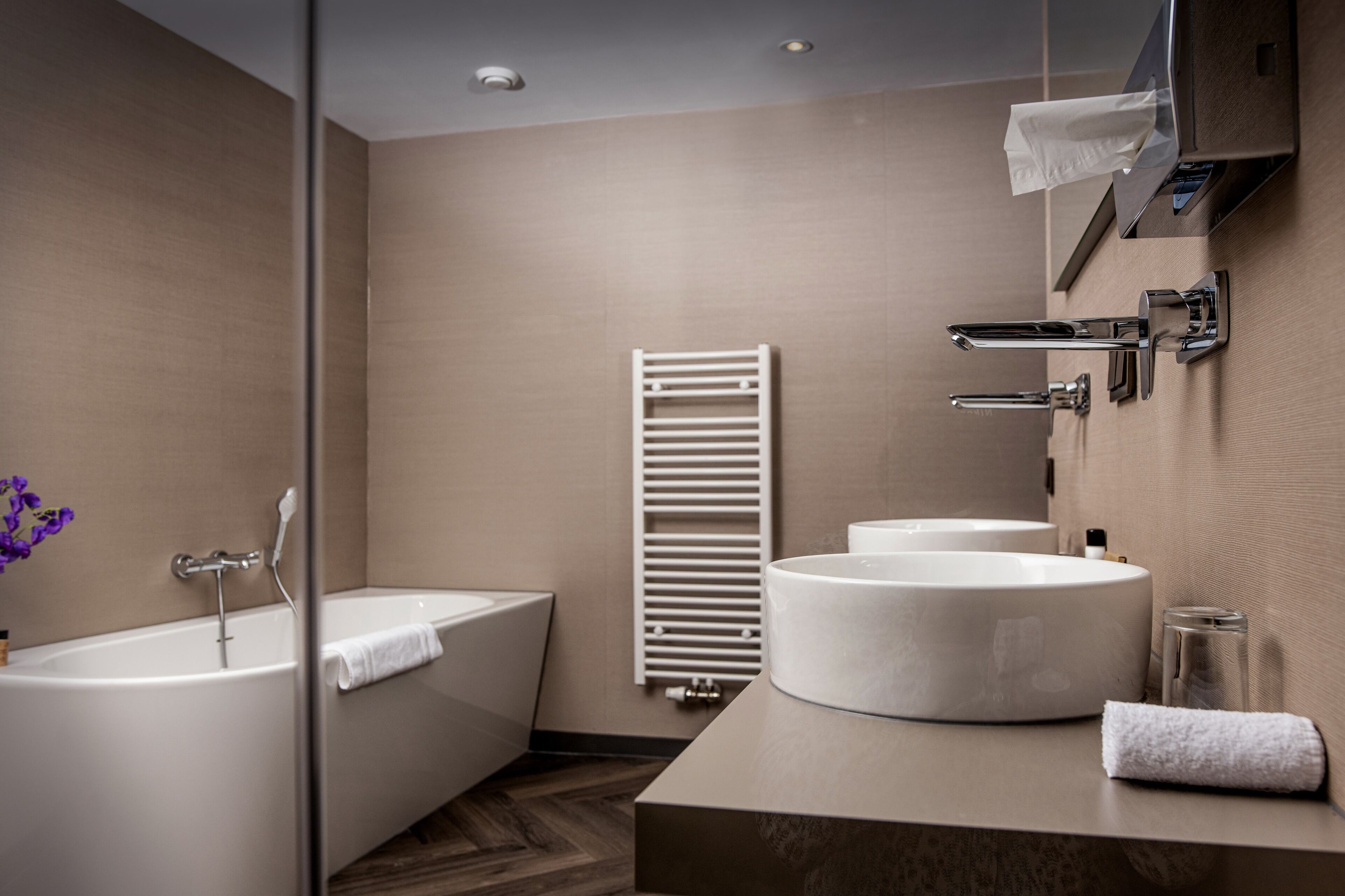 Ein modernes Badezimmer mit Badewanne, zwei Waschbecken und einem Handtuchhalter.